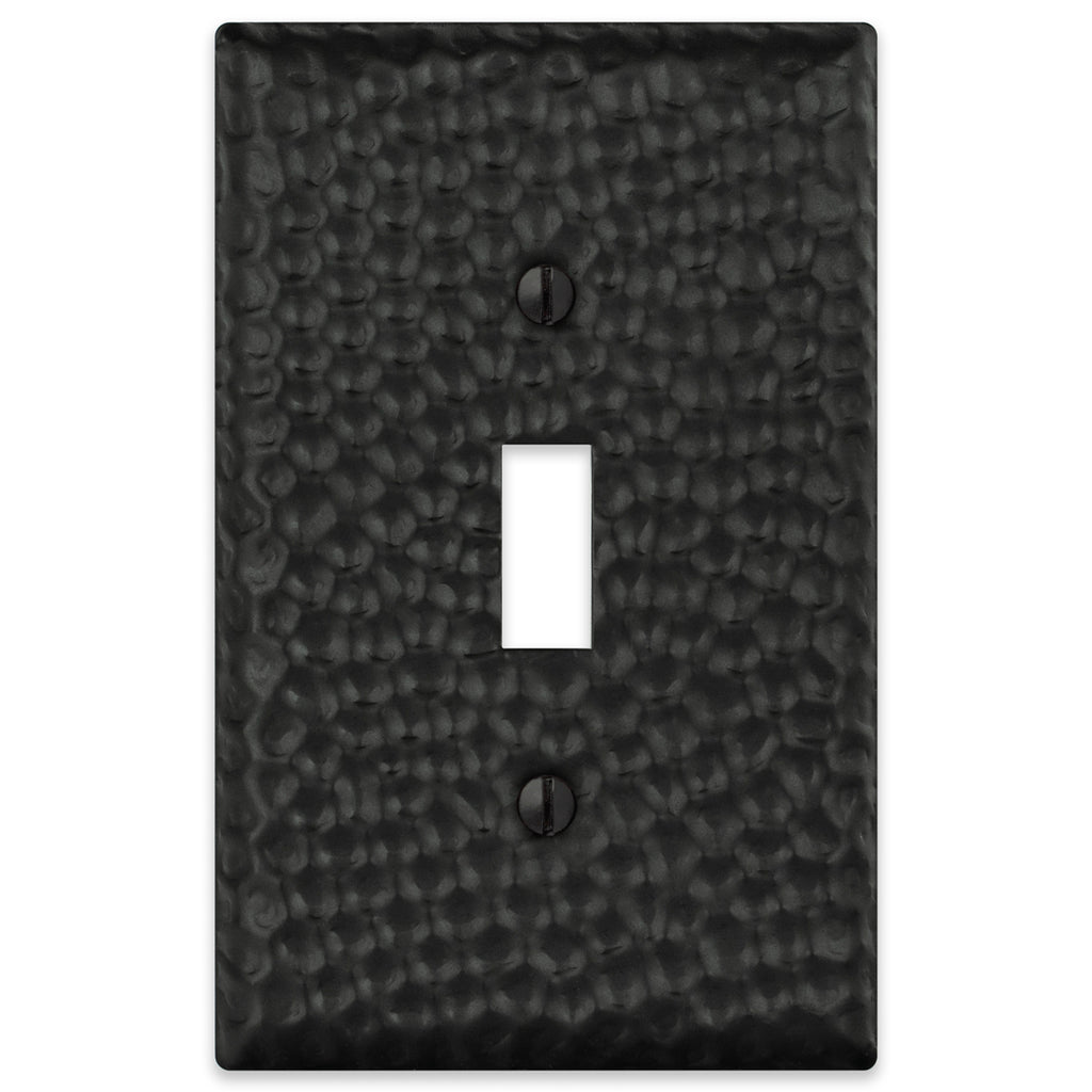 A hammered matte black light switch cover with a textured finish and bold, modern appeal, perfect for adding depth and sophistication to industrial or contemporary interiors.